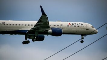 A Delta Air Lines plane approaching for landing, showing its landing gear extended and preparing to touch down