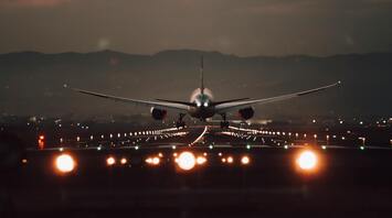 Airplane taking off at dusk with runway lights illuminated