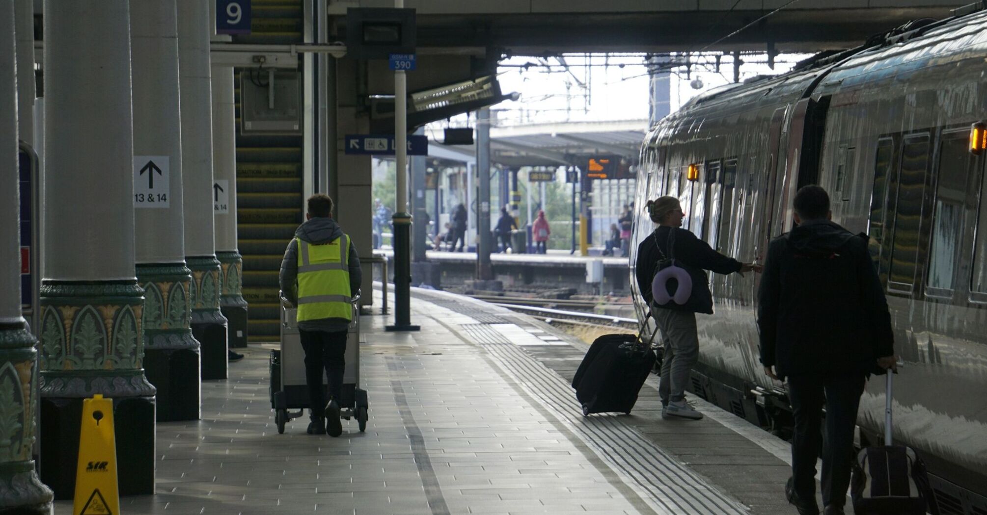 Train platform with passengers boarding and staff working at the station