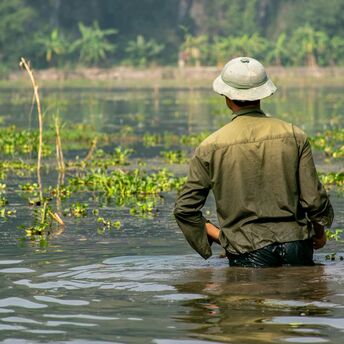 Person wading through floodwater in a green field