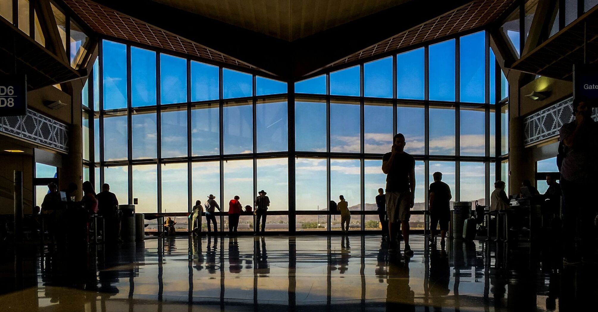 People waiting at an airport near large windows