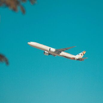 Etihad Airways aircraft in flight against a clear blue sky