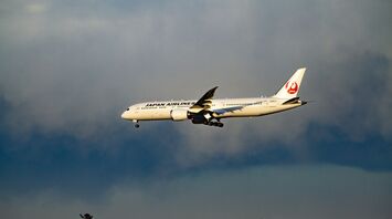 Japan Airlines plane in flight against cloudy sky