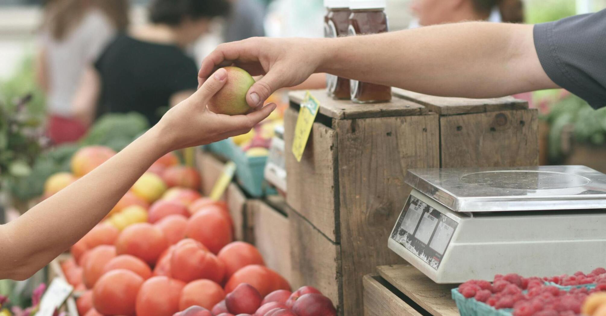 Hand exchanging an apple at a market stall