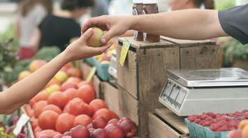 Hand exchanging an apple at a market stall
