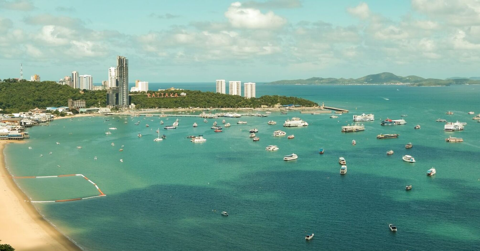 Aerial view of a beach in Thailand with clear turquoise waters and boats anchored near the shore