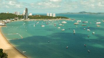 Aerial view of a beach in Thailand with clear turquoise waters and boats anchored near the shore