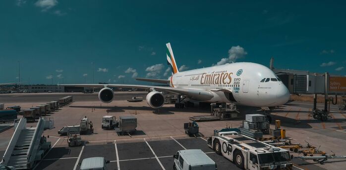 Emirates airplane at the airport gate being prepared for boarding and cargo loading