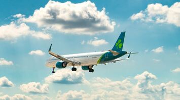 Aer Lingus plane in flight against a bright blue sky with clouds
