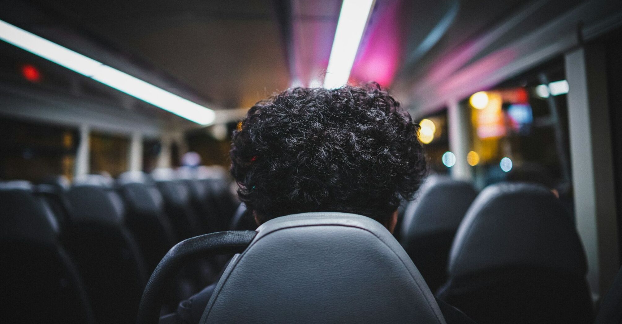 A passenger sits alone on a bus at night