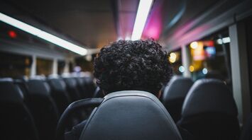 A passenger sits alone on a bus at night
