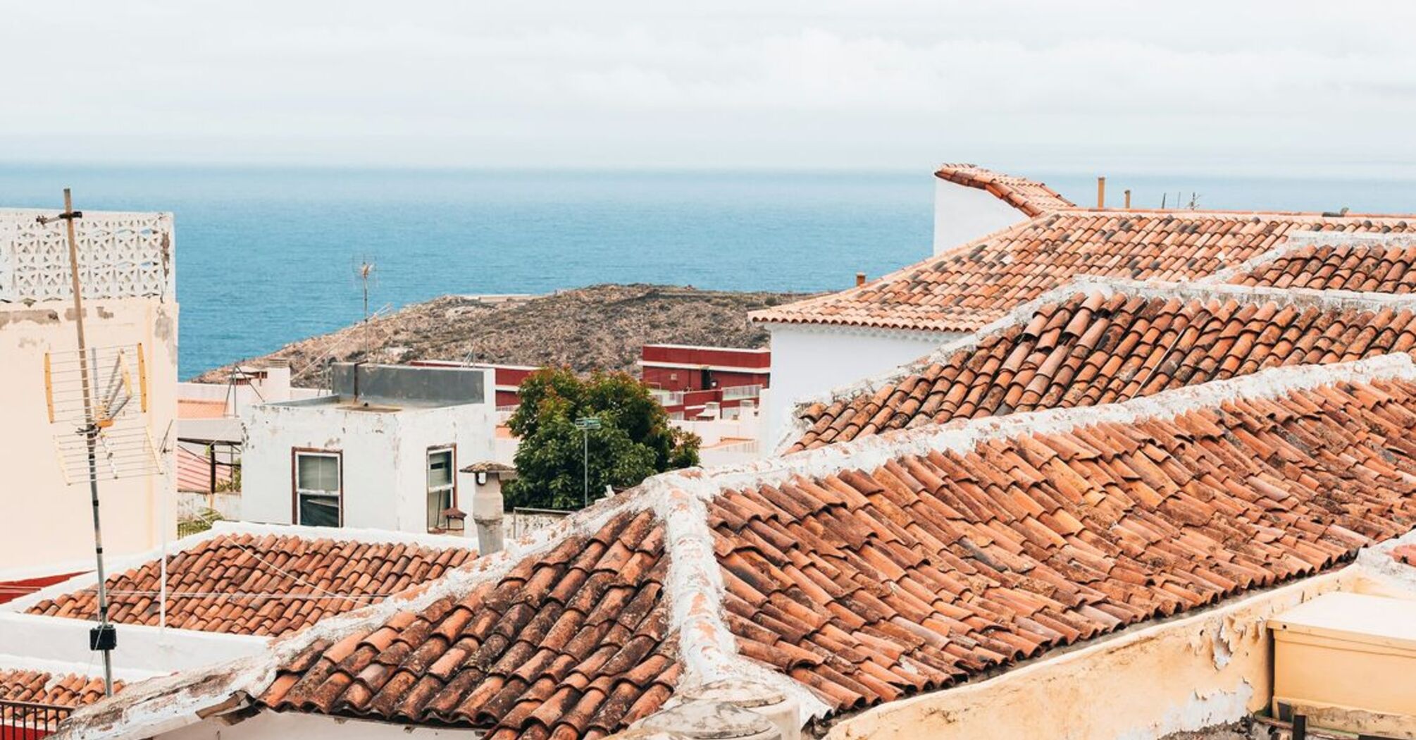 Terracotta-roofed houses in Canary Islands overlooking the ocean on a bright day