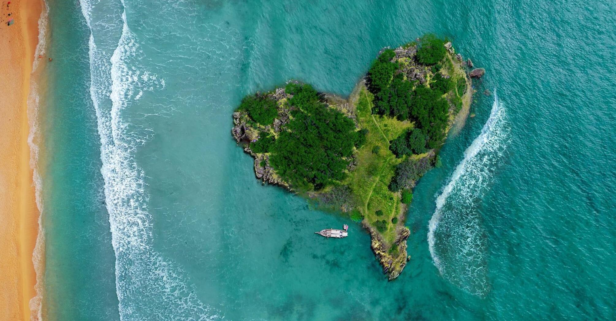 Aerial view of a lush, private island with a boat near a sandy beach