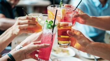 A group of people raising glasses with colorful non-alcoholic beverages in a celebratory toast