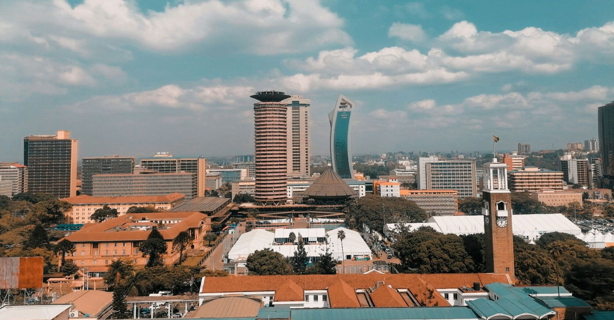 A panoramic view of Nairobi's skyline, featuring modern buildings under a blue sky with scattered clouds