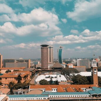 A panoramic view of Nairobi's skyline, featuring modern buildings under a blue sky with scattered clouds