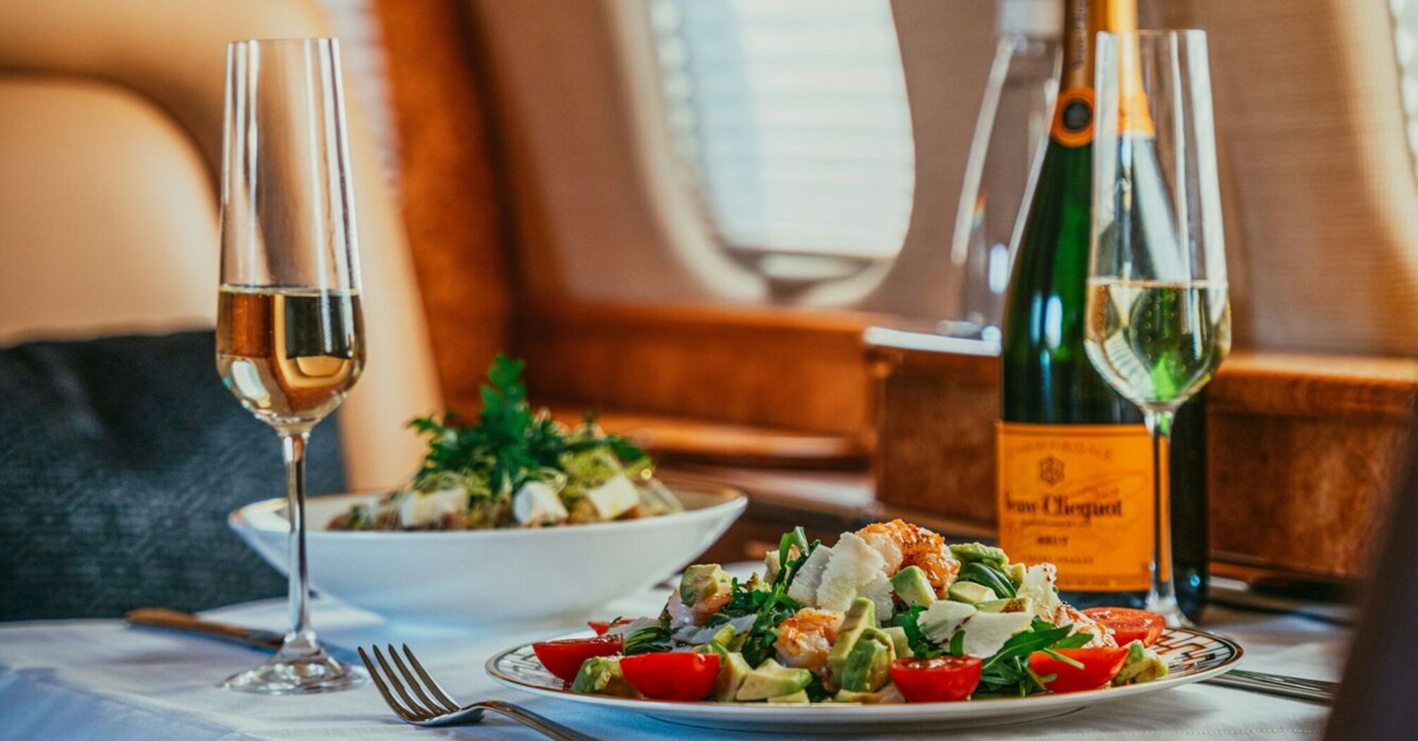 A luxurious in-flight meal served on a private jet, featuring a gourmet salad and champagne