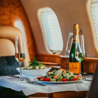 A luxurious in-flight meal served on a private jet, featuring a gourmet salad and champagne