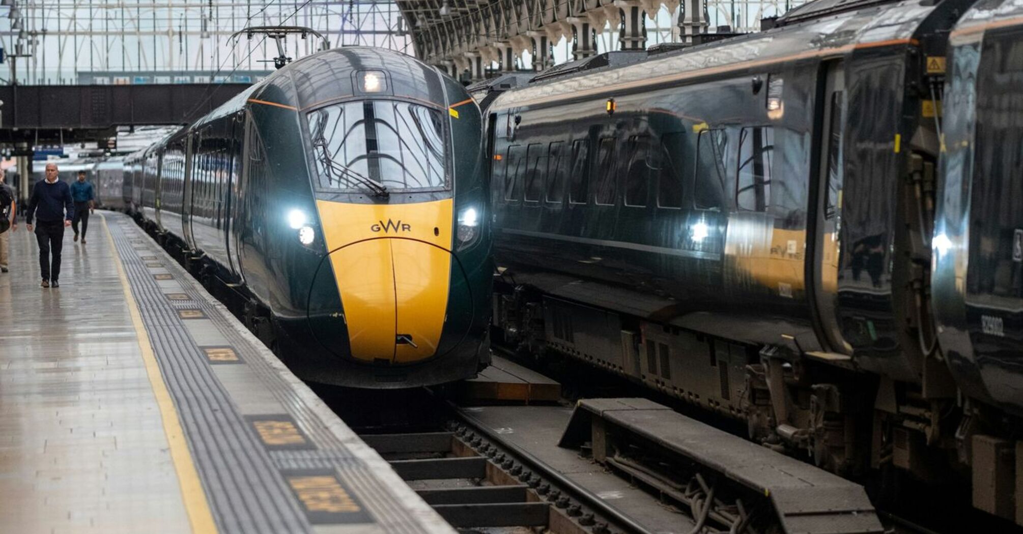 A GWR train at a station platform under an arched glass roof, preparing for departure