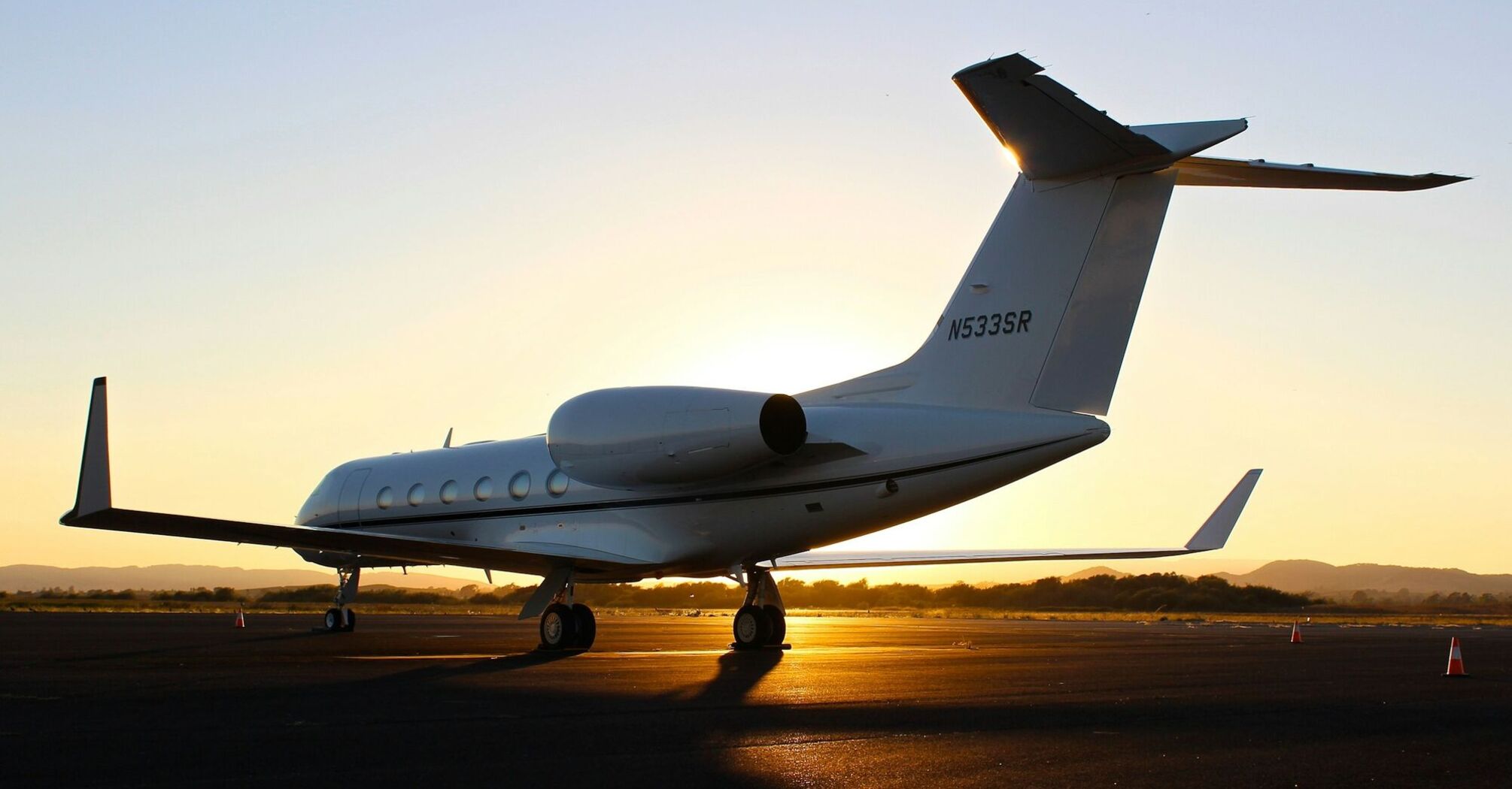 Small plane parked on runway at sunset