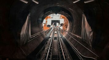 View inside a dark railway tunnel with tracks leading towards the exit