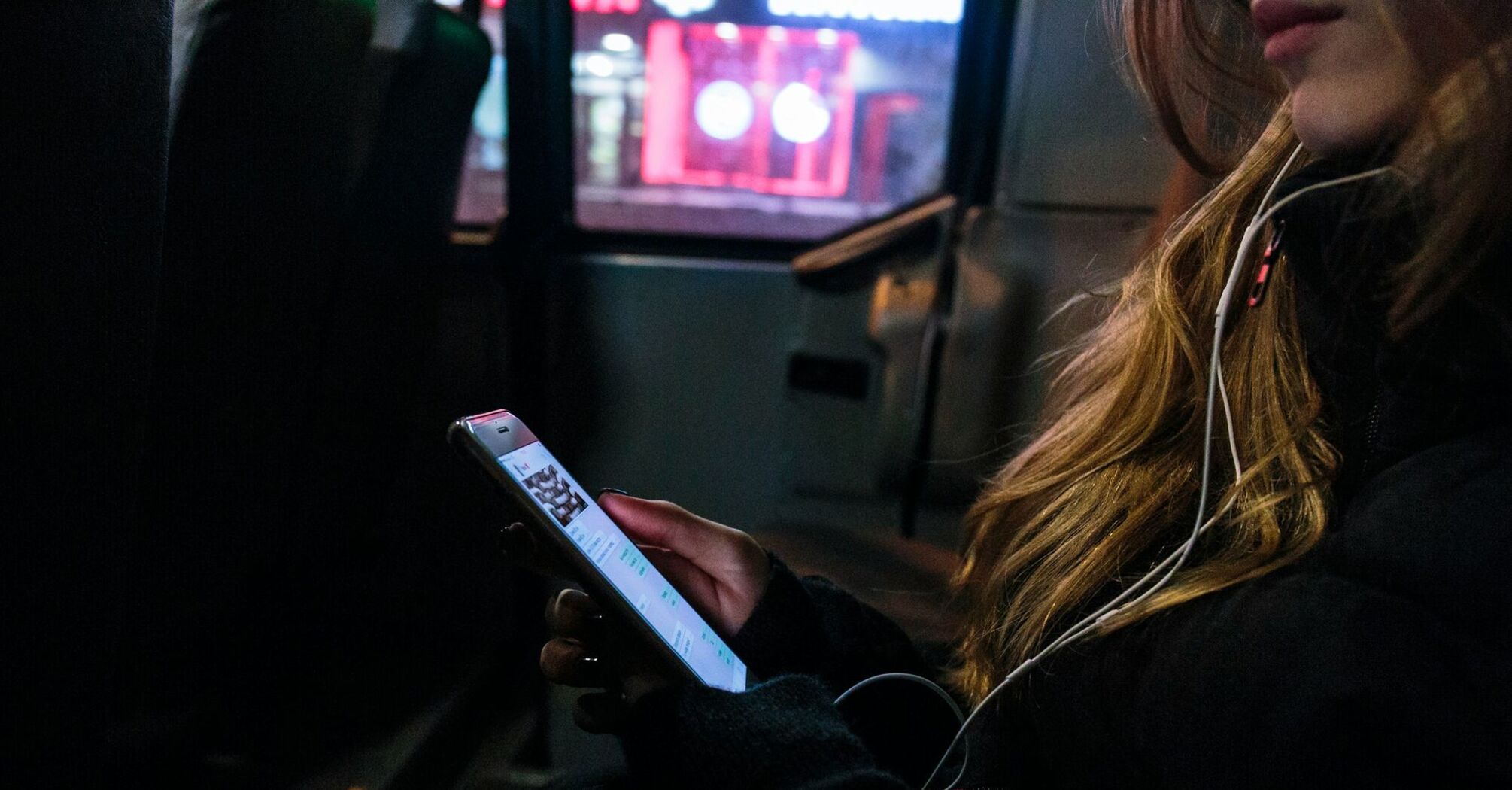 A person using a phone on a bus at night