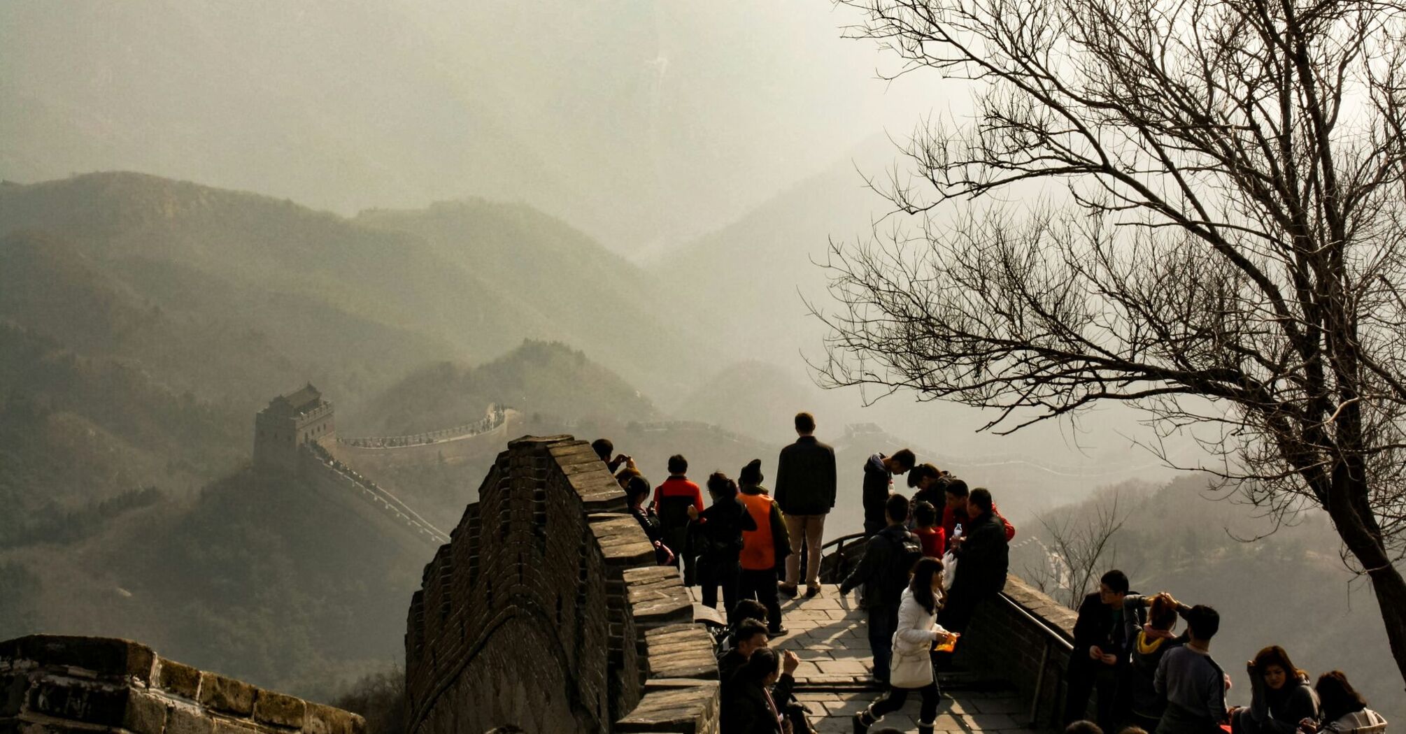 Tourists walking on the Great Wall of China with misty mountains in the background