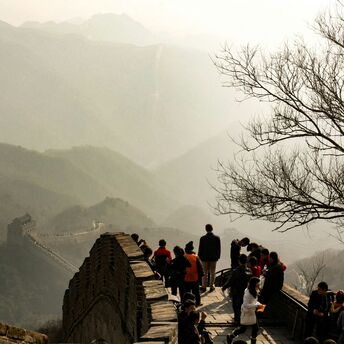 Tourists walking on the Great Wall of China with misty mountains in the background