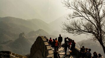 Tourists walking on the Great Wall of China with misty mountains in the background