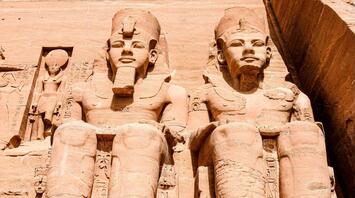 Statues of pharaohs and deities carved into the facade of the Great Temple at Abu Simbel, showcasing ancient Egyptian craftsmanship under a clear blue sky