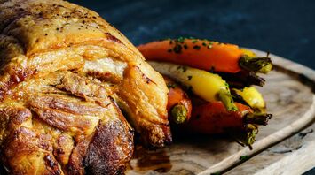Roast meat with colorful carrots served on a wooden board
