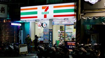 Night view of a 7-Eleven convenience store with motorcycles parked outside