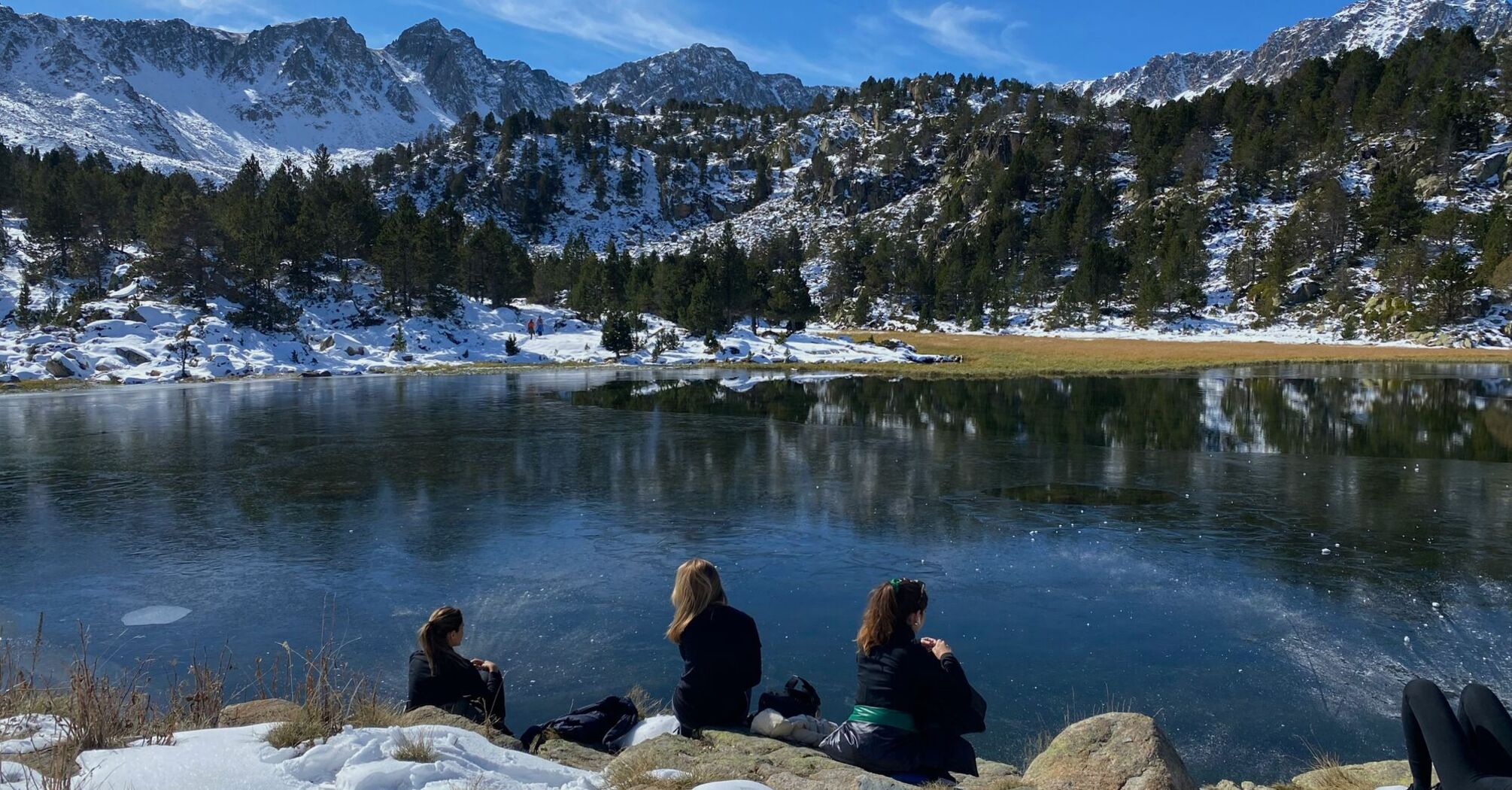 people sitting on rock near lake during daytime