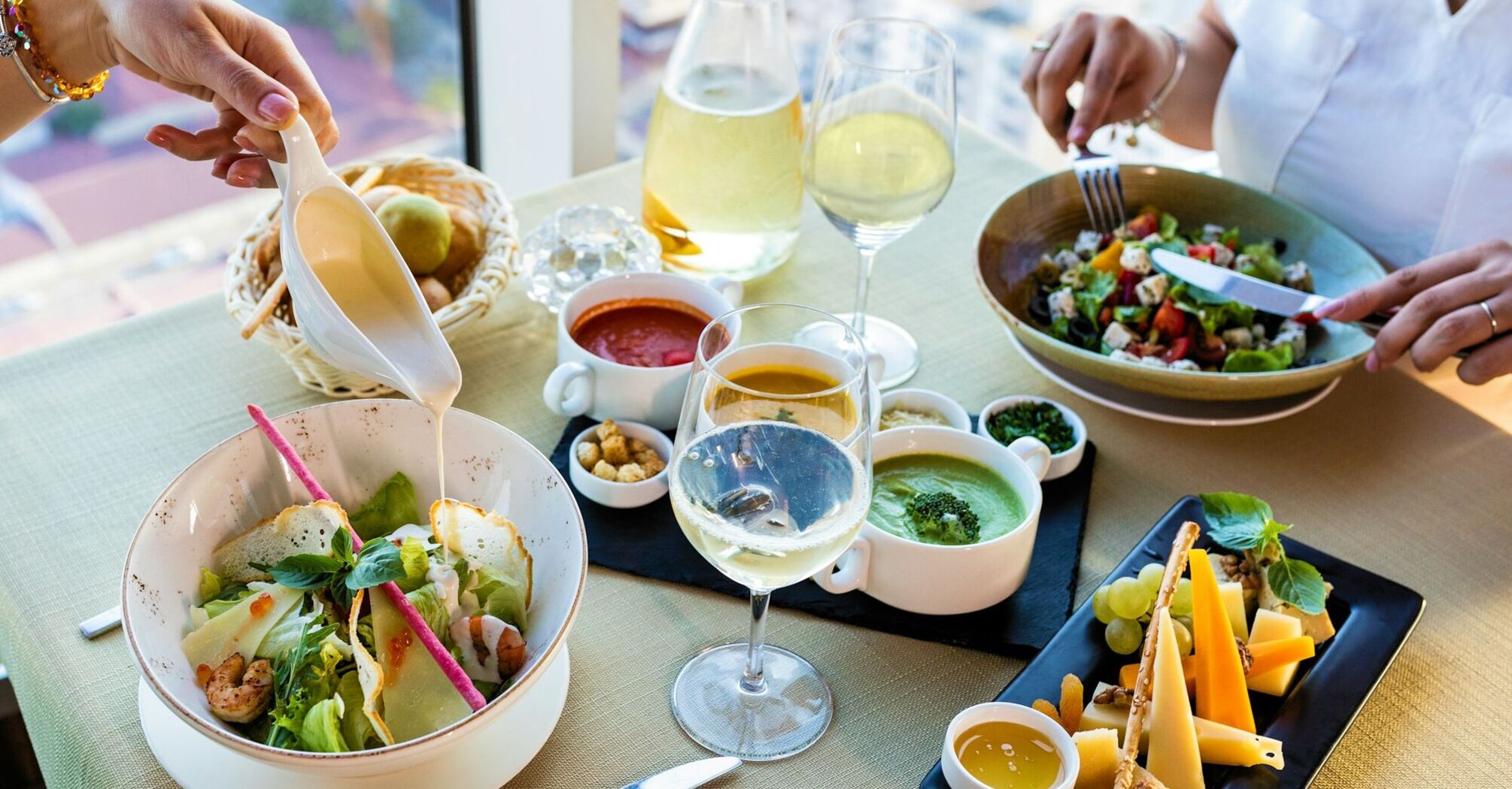 A table set with salads, sauces, cheese, and wine, showcasing a culinary dining experience