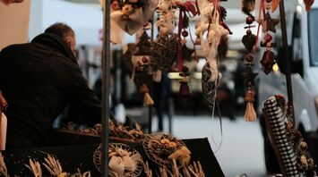 A vendor stall at the Weimar Onion Market displaying decorative onion garlands and dried floral arrangements under soft lights
