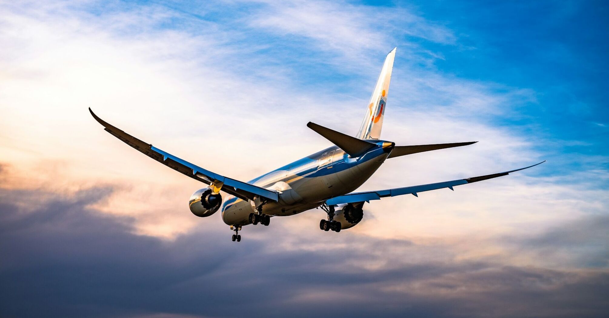 Airplane descending at sunset with cloudy sky