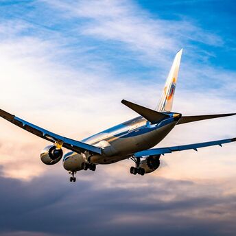 Airplane descending at sunset with cloudy sky