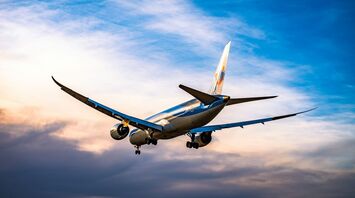 Airplane descending at sunset with cloudy sky
