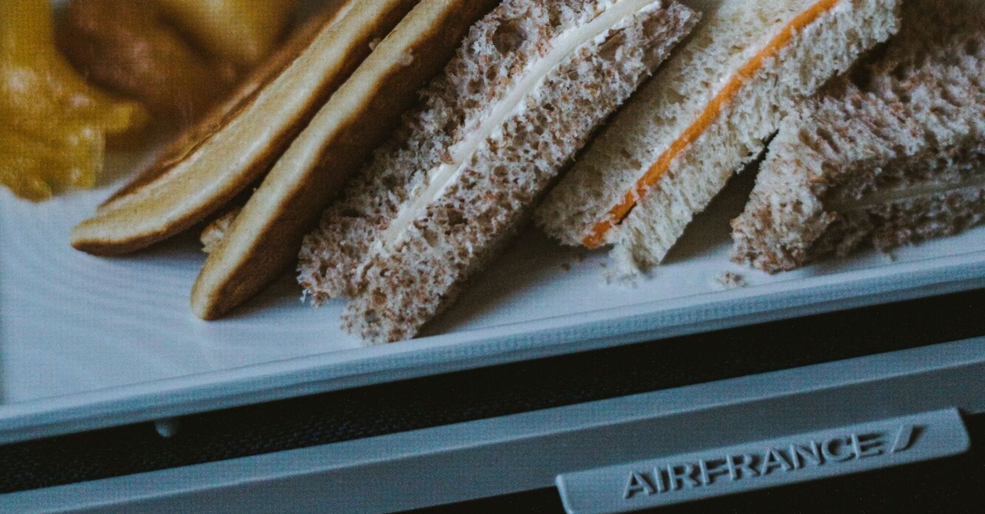 A tray with sandwiches and snacks served on an Air France flight, featuring bread with various fillings and sides