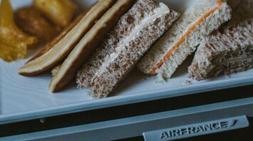 A tray with sandwiches and snacks served on an Air France flight, featuring bread with various fillings and sides