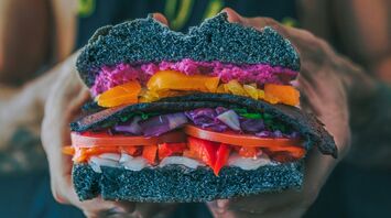 Colorful plant-based burger held by person wearing a vegan t-shirt