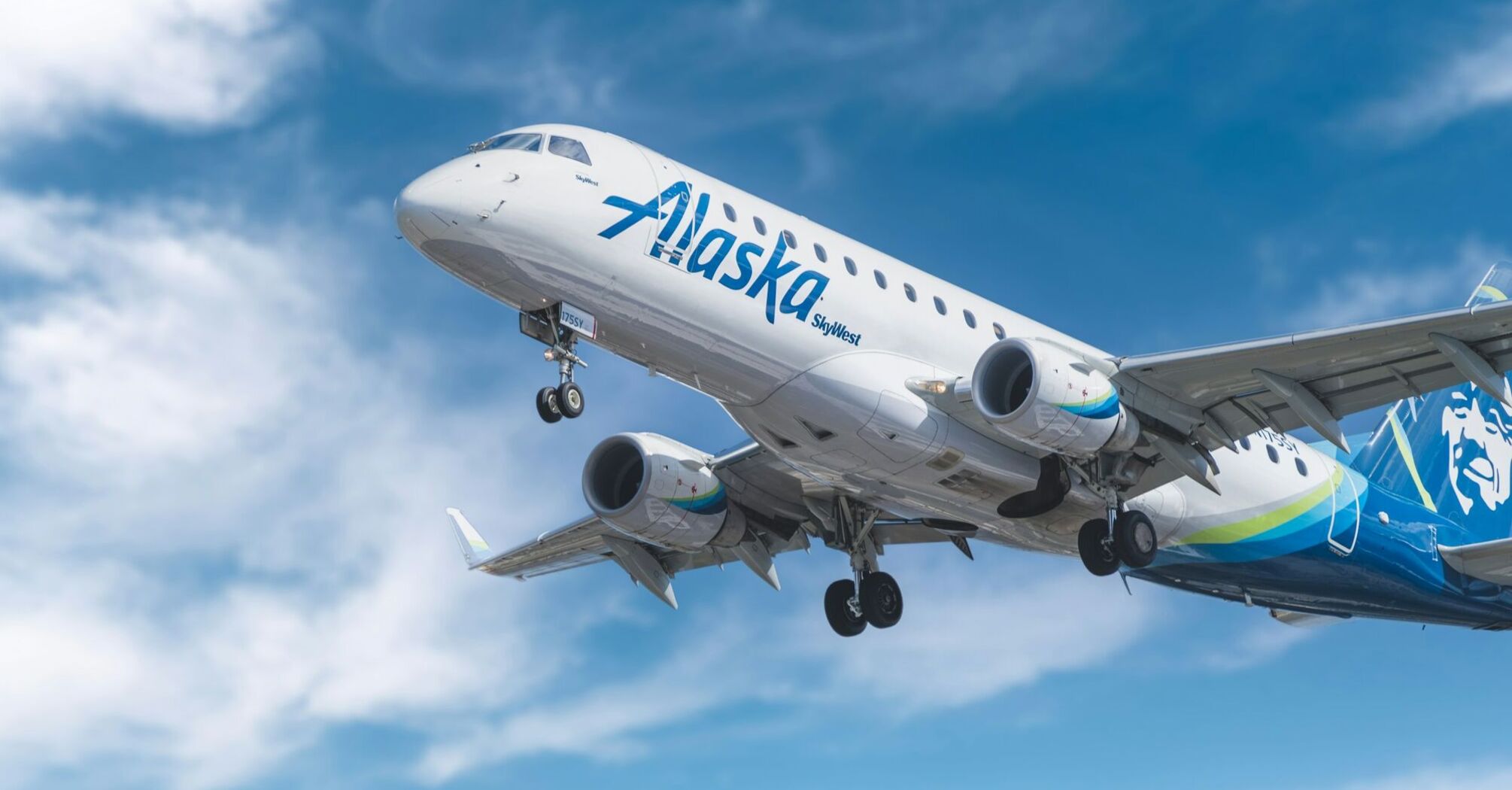 Alaska Airlines aircraft in flight against a bright blue sky