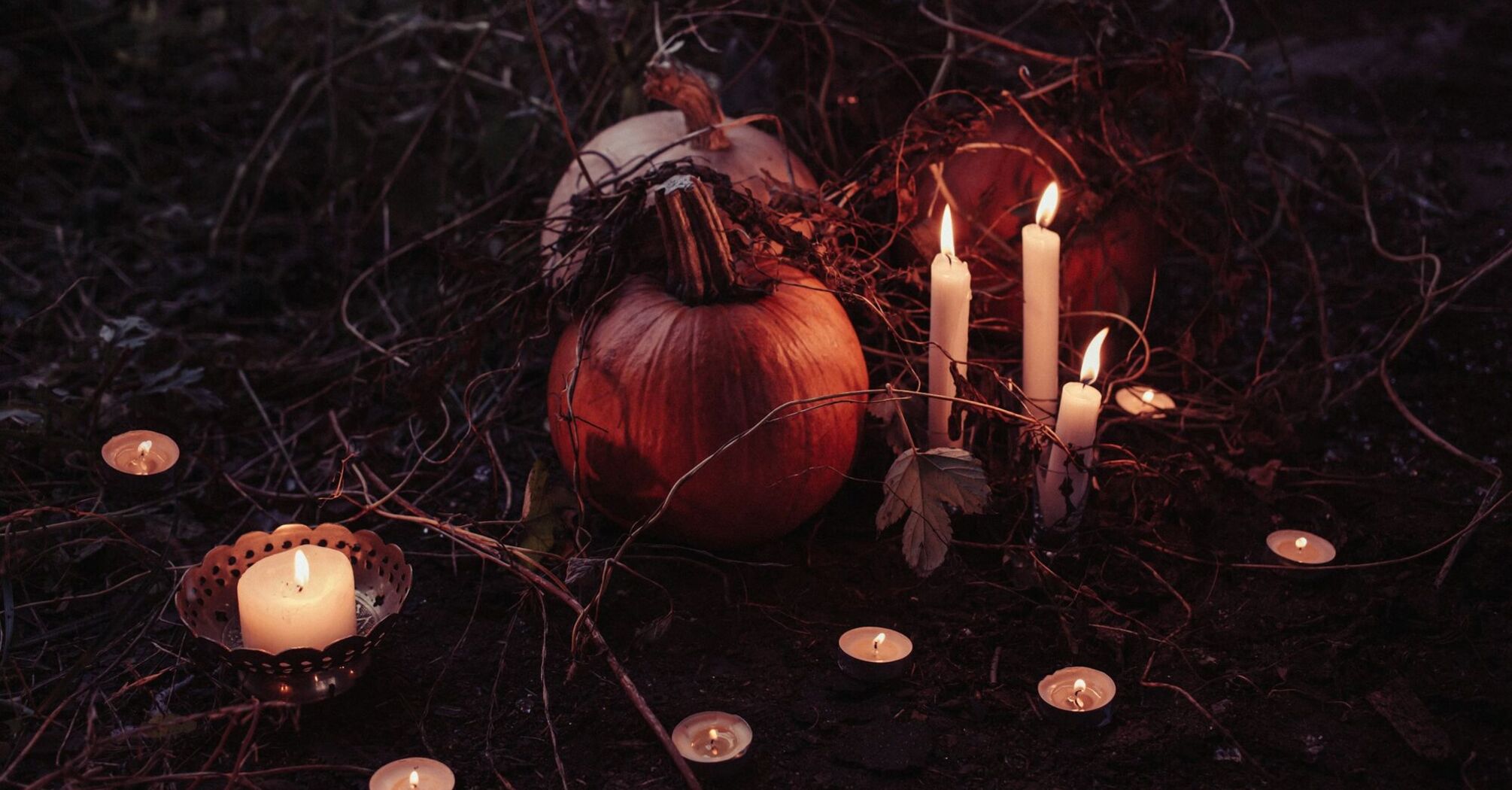 Pumpkins and candles arranged in a dark, eerie setting