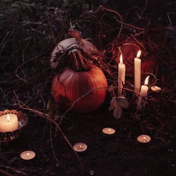 Pumpkins and candles arranged in a dark, eerie setting