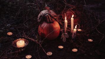 Pumpkins and candles arranged in a dark, eerie setting