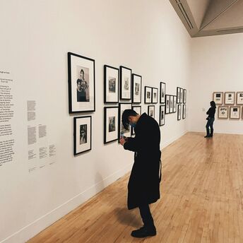 Visitor observing framed photographs in an art gallery
