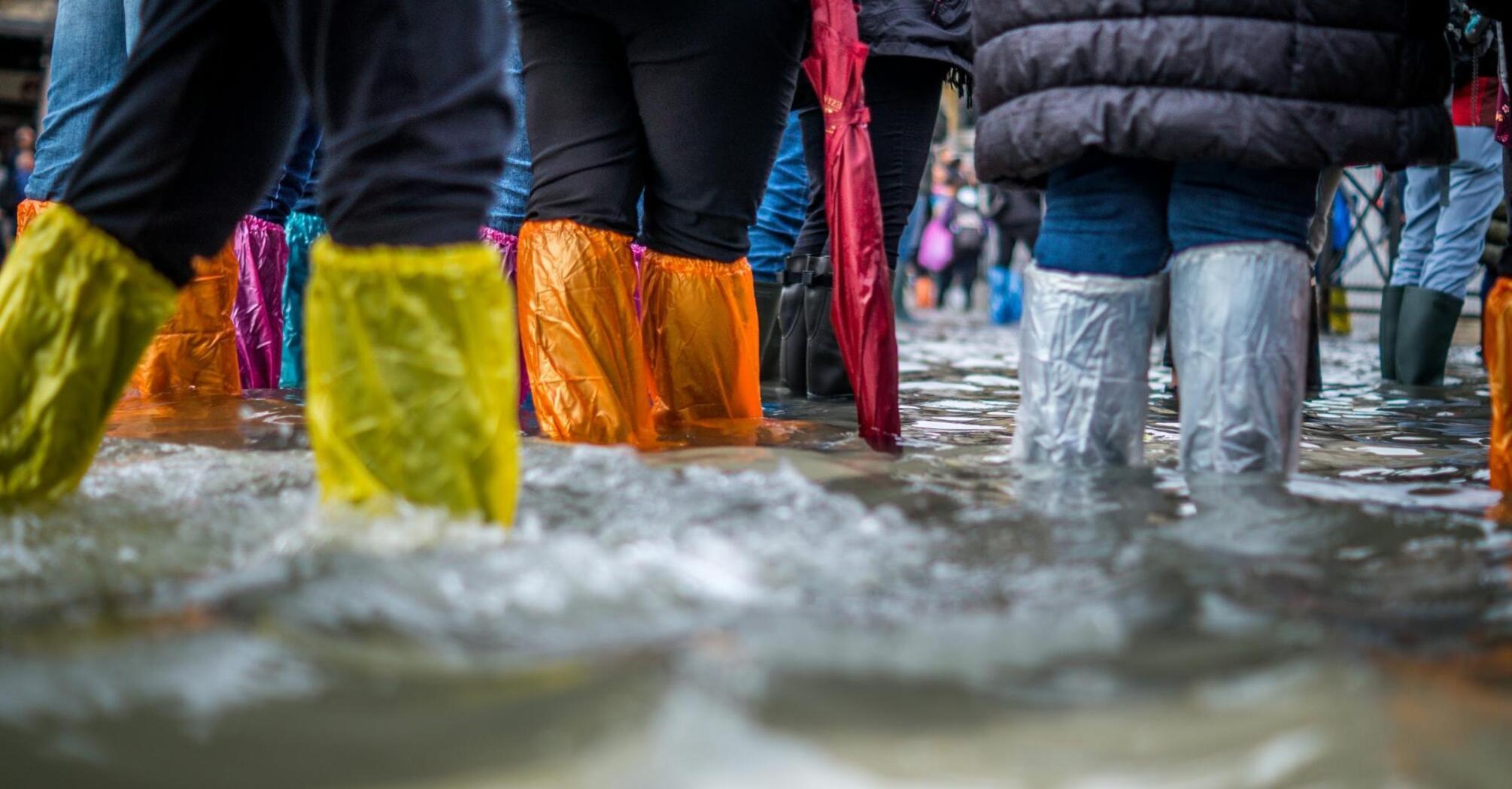 People walking through floodwaters with colorful waterproof boots