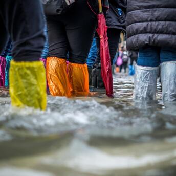 People walking through floodwaters with colorful waterproof boots