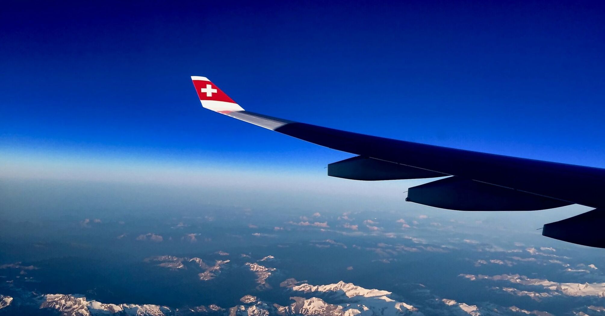 View of Swiss Alps from an airplane window with SWISS airline wing