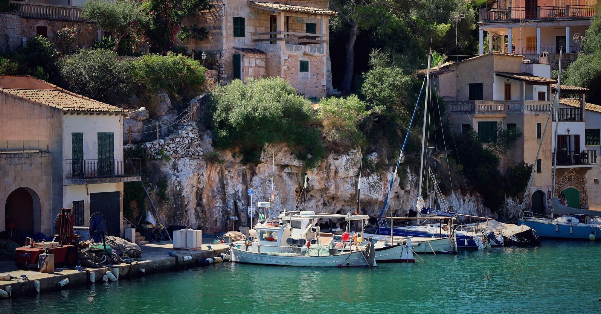 Scenic view of boats docked by rustic cliffside houses in Mallorca